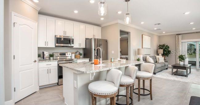 A modern kitchen features white cabinets, granite countertops, stainless steel appliances, and a breakfast bar — 57 ENCLAVE AVENUE, PALM COAST, FL