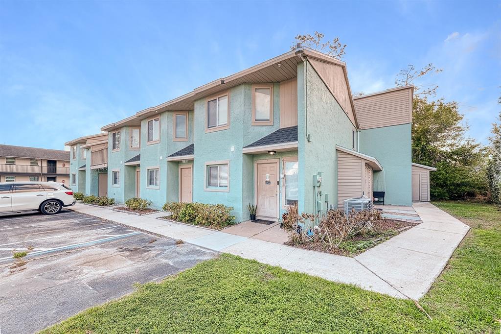 A two-story, light green stucco apartment building with a sidewalk and parking lot in front — 283 GARDNER LANE UNIT F, KISSIMMEE, FL