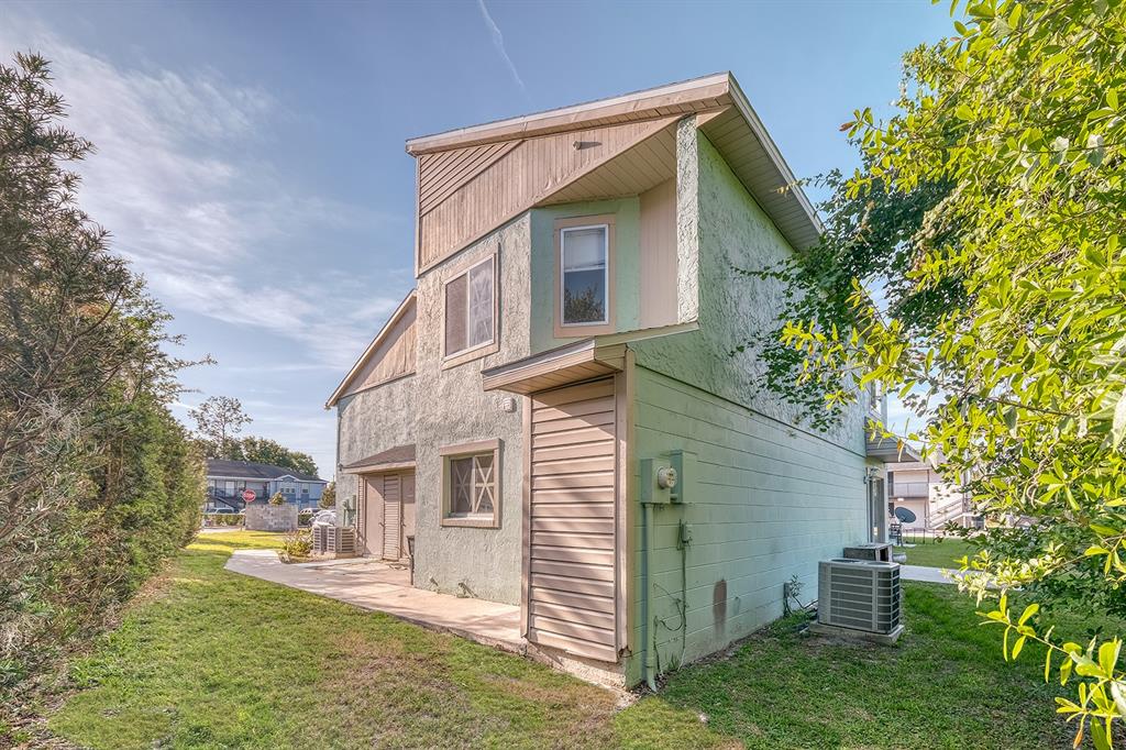 A two-story light green stucco building with a small patio and an outdoor air conditioner — 283 GARDNER LANE UNIT F, KISSIMMEE, FL