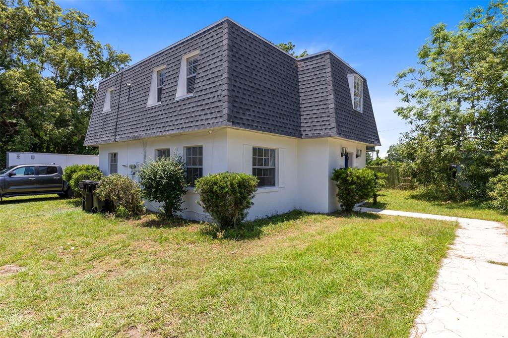 A two-story house with a mansard roof stands on a grassy lot with trees — 1228 E MURIEL STREET, ORLANDO, FL