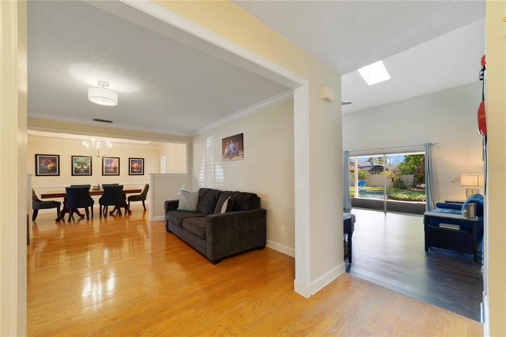 A living room features hardwood floors, a dark sofa, a grey armchair, and plantation shutters — 749 WILLOW RUN LANE, WINTER SPRINGS, FL