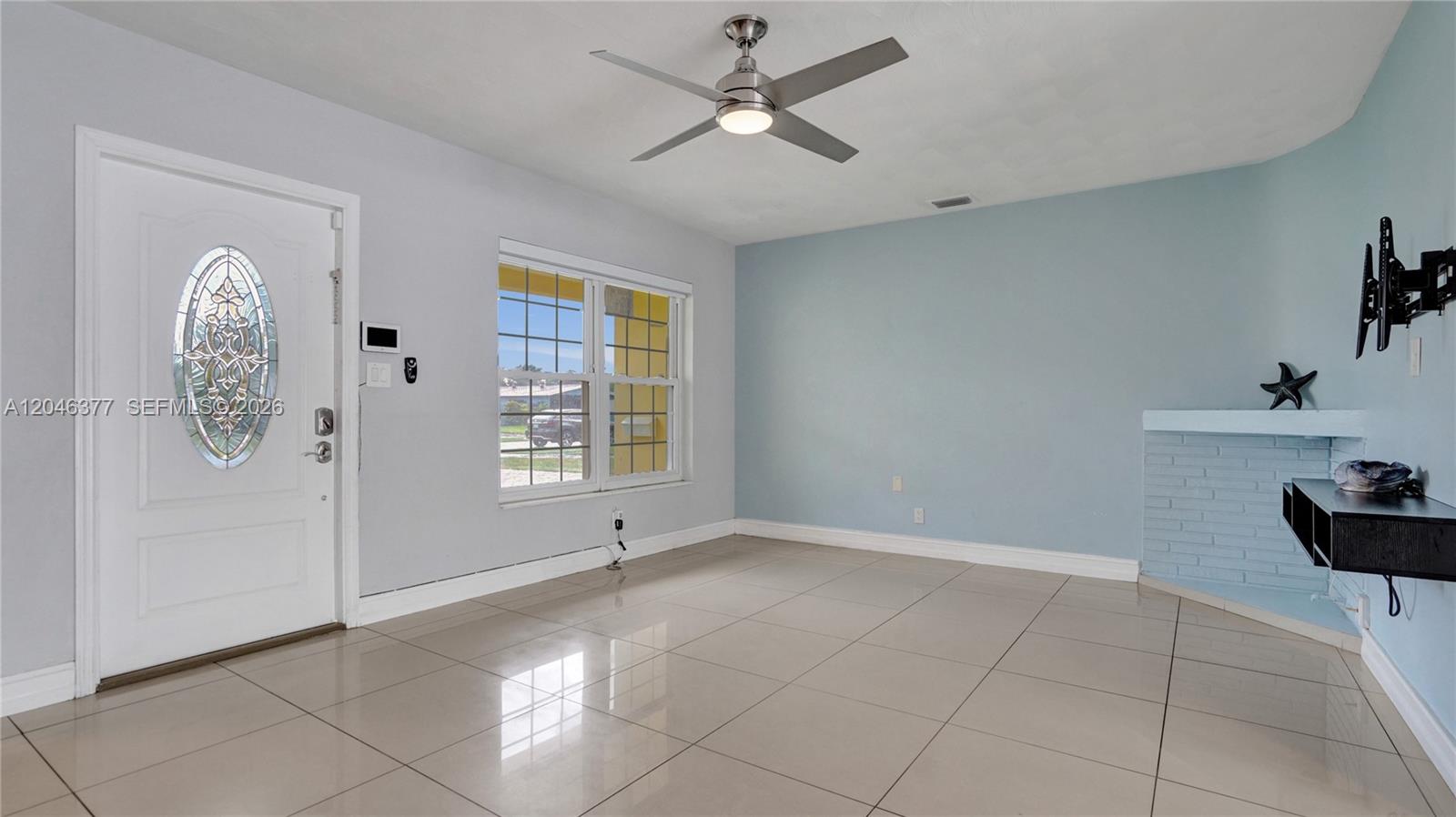 A living room features light blue walls, tile flooring, a ceiling fan, and a fireplace — 6431 S Coolidge St, Hollywood FL 33024, HOLLYWOOD, FL