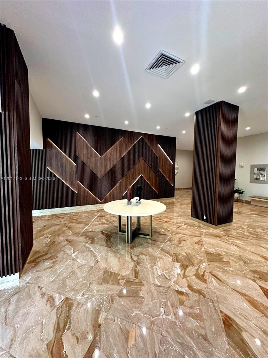 A lobby features a round table, marble flooring, and a chevron-patterned wood accent wall — 1370 S Ocean Blvd # 902, Pompano Beach FL 33062, POMPANO BEACH, FL