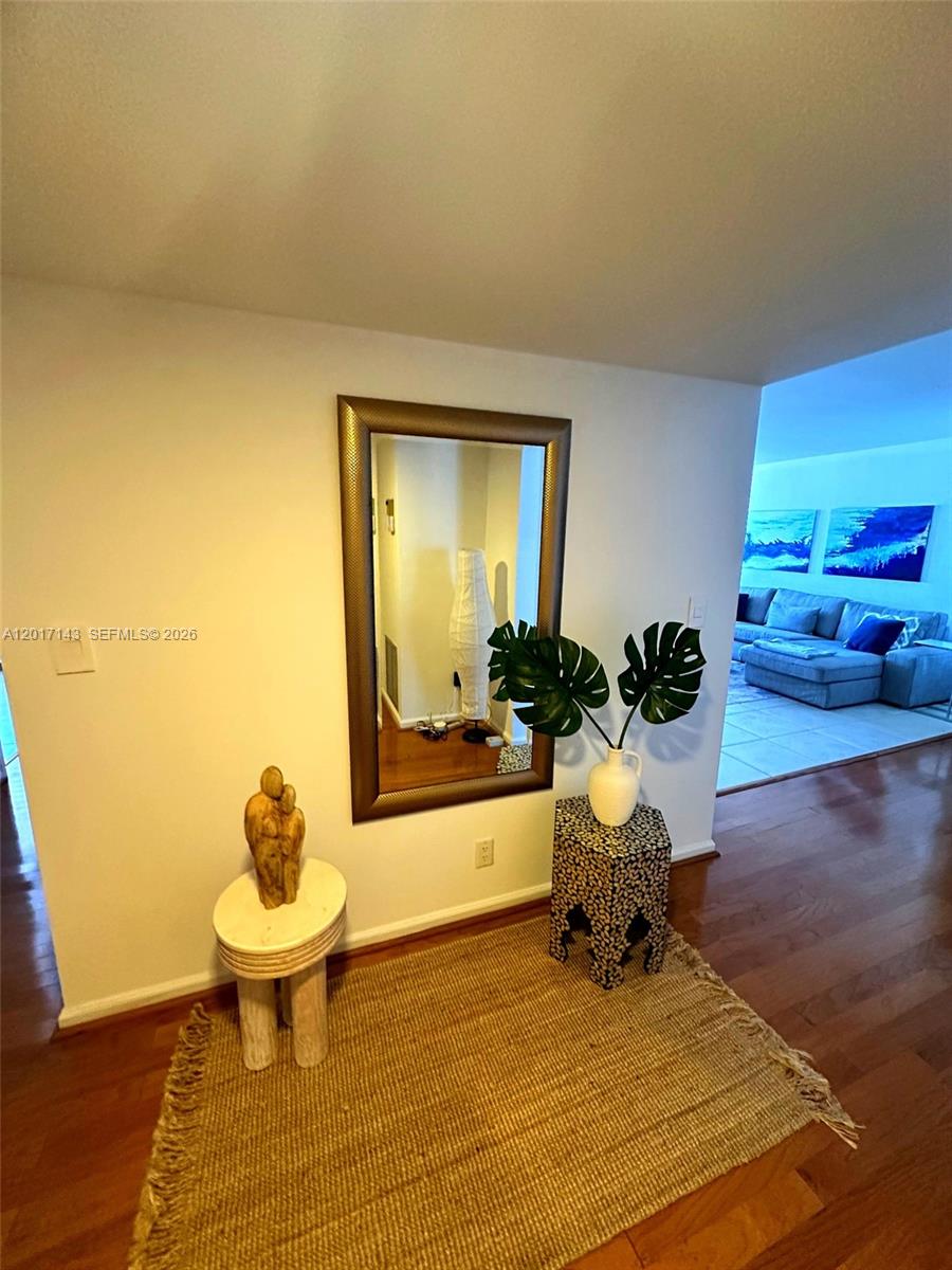 A foyer features a mirror, two small tables, a rug, and a view into a living room — 1370 S Ocean Blvd # 902, Pompano Beach FL 33062, POMPANO BEACH, FL
