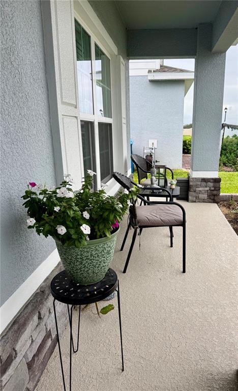 A covered porch features a potted plant on a stand and two chairs — 1562 LANDON LANE, HAINES CITY, FL