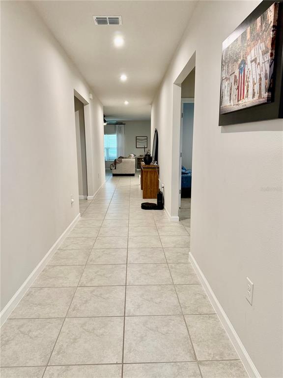 A long hallway with light-colored tile flooring leads toward a living area — 1562 LANDON LANE, HAINES CITY, FL