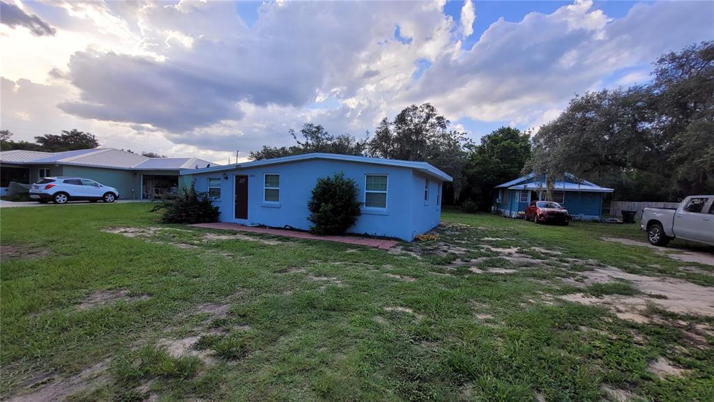 A light blue, single-story house with a flat roof sits on a grassy, sandy lot — 3013 LAUREL AVENUE, LAKE WALES, FL