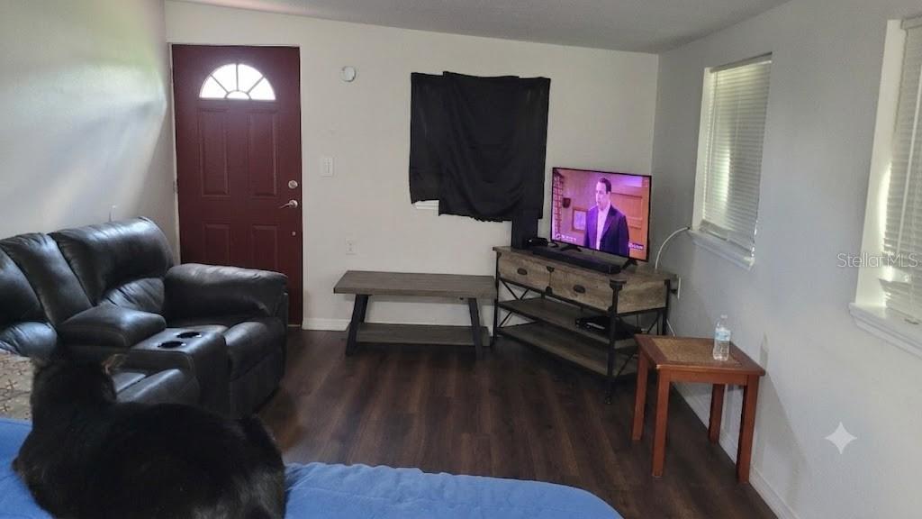 A living room features a dark leather sofa, a television on a stand, and wood flooring — 3013 LAUREL AVENUE, LAKE WALES, FL