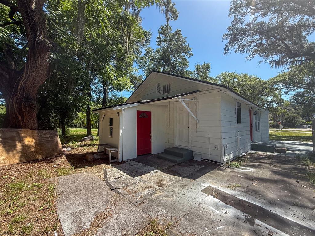 The exterior of a white house features a red door and a concrete driveway — 1002 TILDEN AVENUE, APOPKA, FL