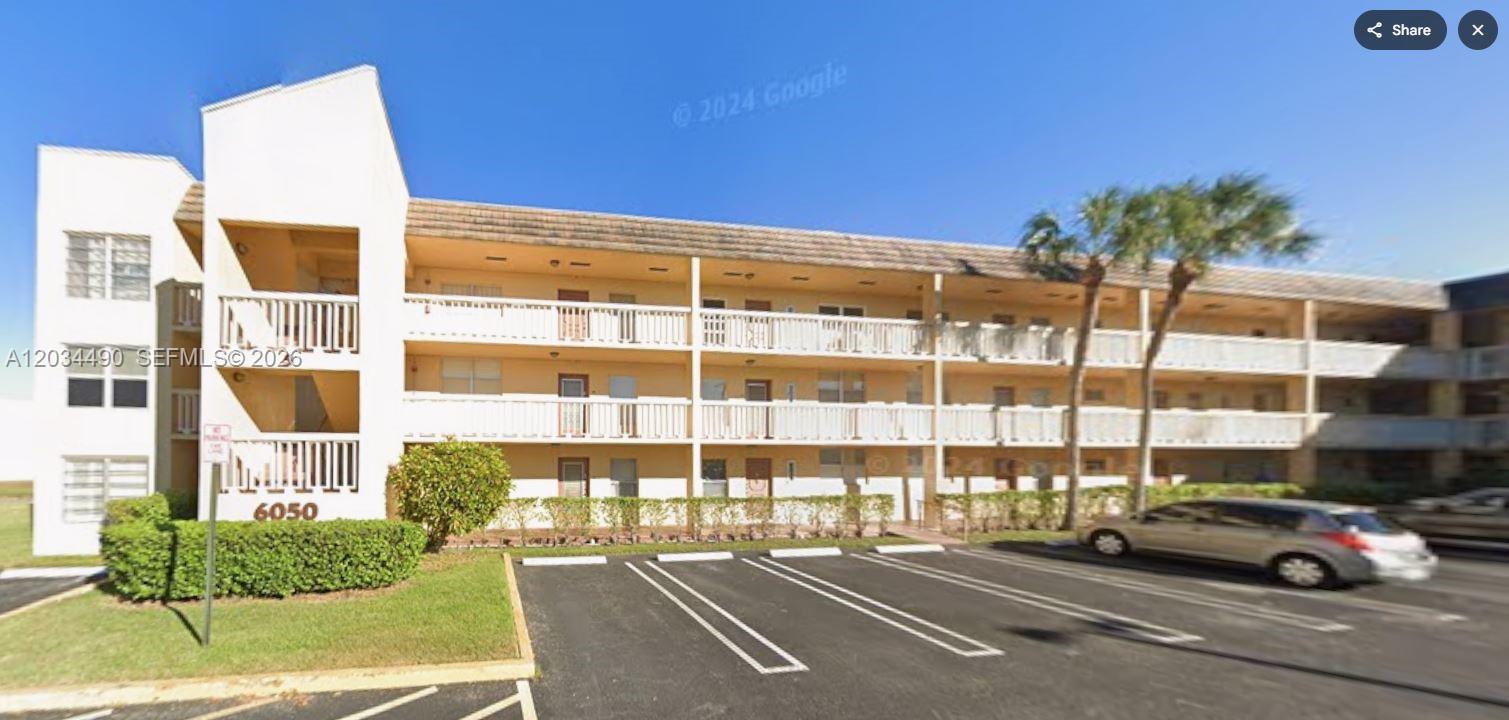 A three-story apartment building with a parking lot in front and palm trees — 6050 NW 64th Ave # 105, Tamarac FL 33319, TAMARAC, FL