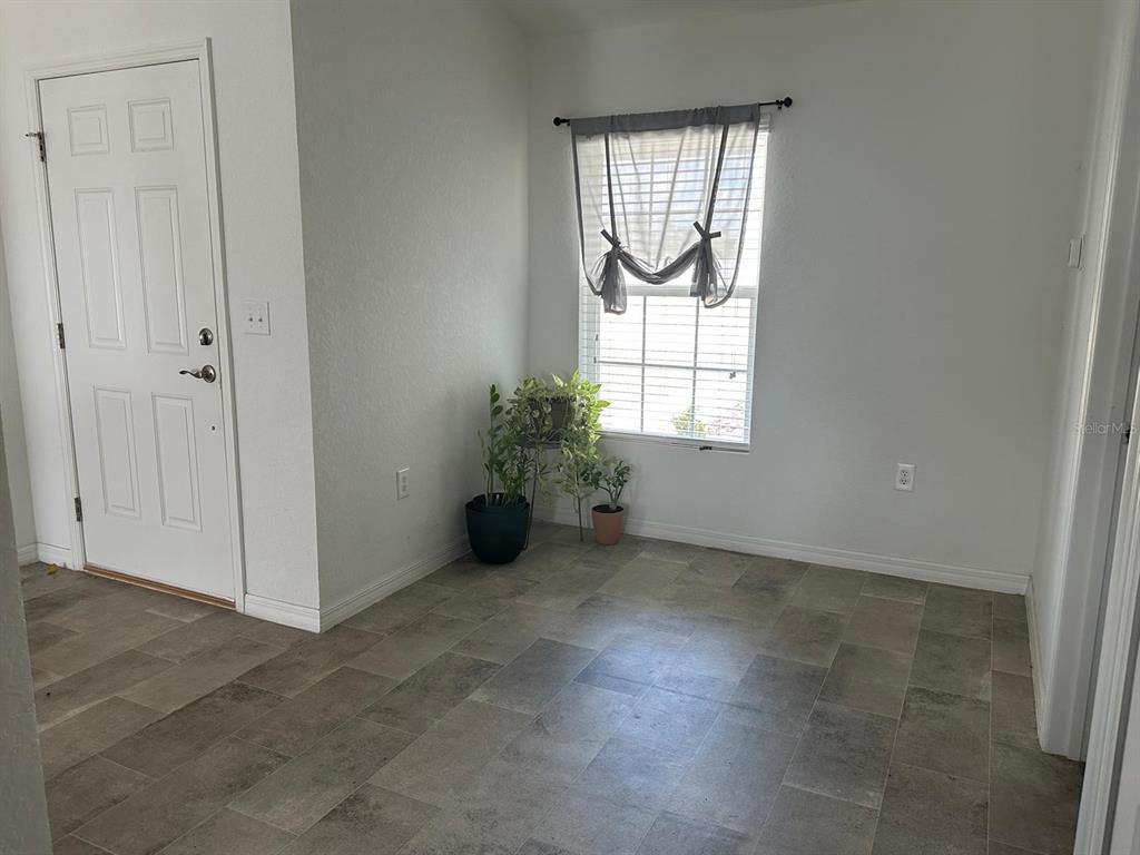 A room with gray tile flooring, a white door, and a window with a curtain — 1116 CALOOSA RIDGE WAY, BABSON PARK, FL