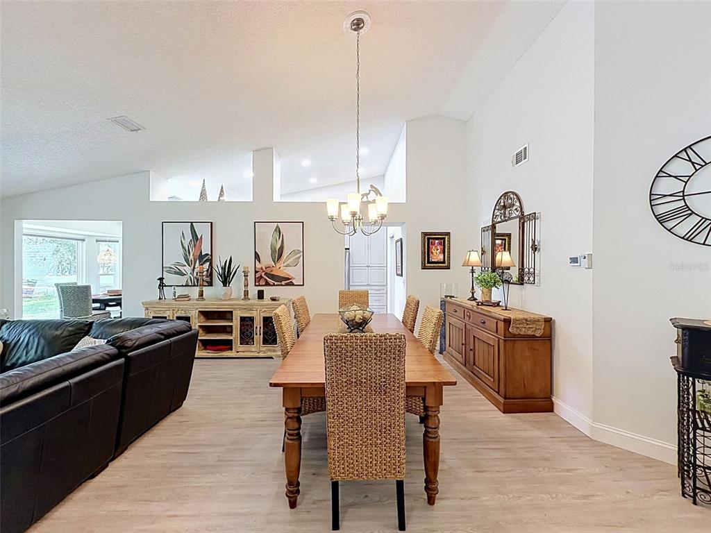 A dining area features a wooden table with wicker chairs, a chandelier, and two sideboards — 7442 WOODHOLLOW ROAD, SPRING HILL, FL