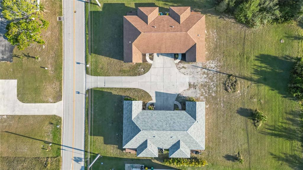 An aerial view shows two houses with different colored roofs sharing a concrete driveway — 49 BOUNDARY BOULEVARD UNIT B, ROTONDA WEST, FL