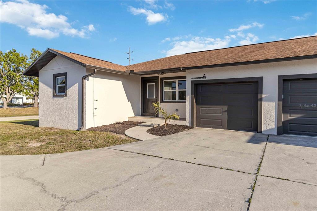 A single-story house exterior features a concrete driveway, a garage, and a small front yard — 49 BOUNDARY BOULEVARD UNIT B, ROTONDA WEST, FL