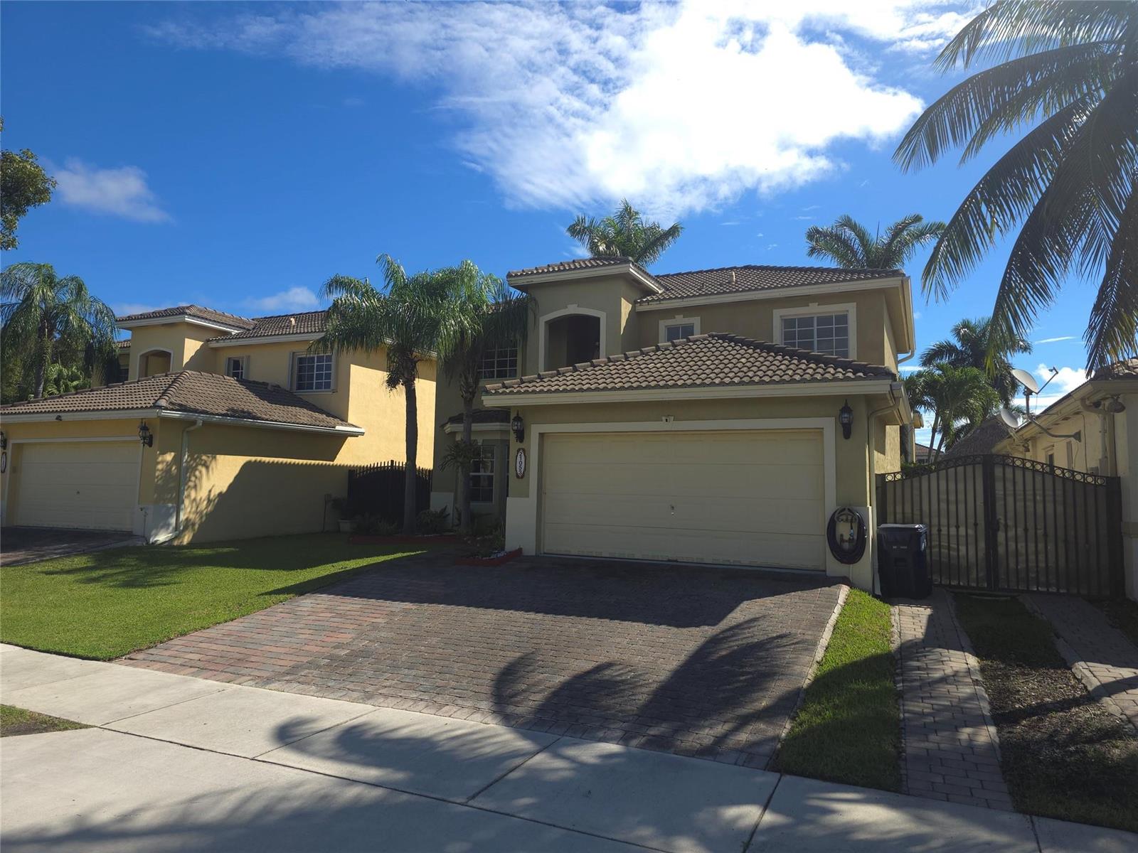A two-story tan house with a tiled roof, paver driveway, and palm trees — 21053 SW 88th Place, Cutler Bay FL 33189, CUTLER BAY, FL