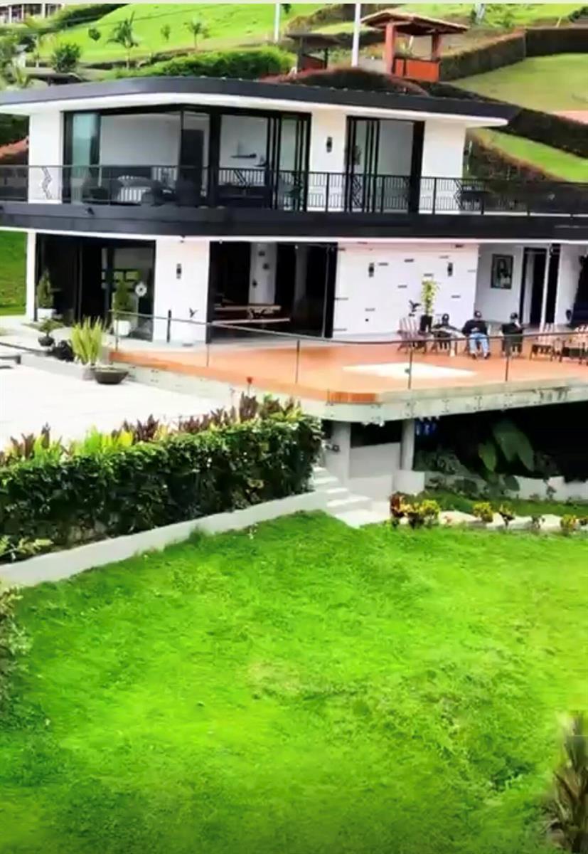 A modern two-story house with a large terrace, glass walls, and a grassy lawn — Los Altos Del Penol El Penol, FL
