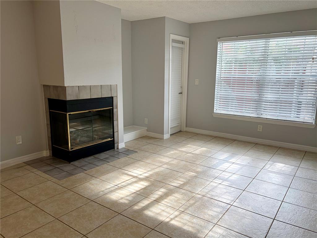 A living room features light tile flooring, a corner fireplace, and a large window — 10200 GANDY BOULEVARD N UNIT 915, ST PETERSBURG, FL
