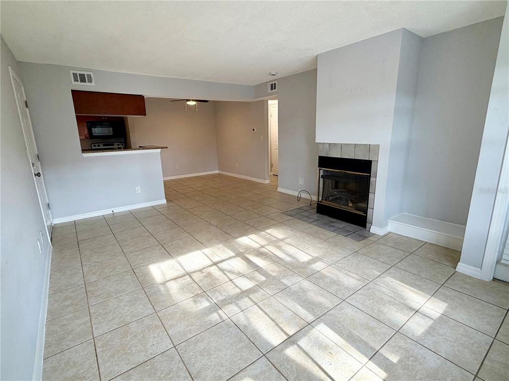 A living room with tile flooring, a fireplace, and an open view into the kitchen — 10200 GANDY BOULEVARD N UNIT 915, ST PETERSBURG, FL