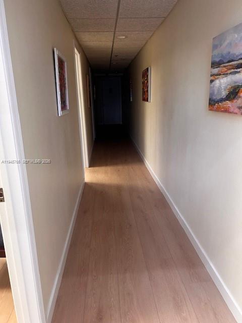 A long hallway features light wood-look flooring, beige walls, and two framed pieces of art — 13318 SW 128th St, Miami FL 33186, MIAMI, FL