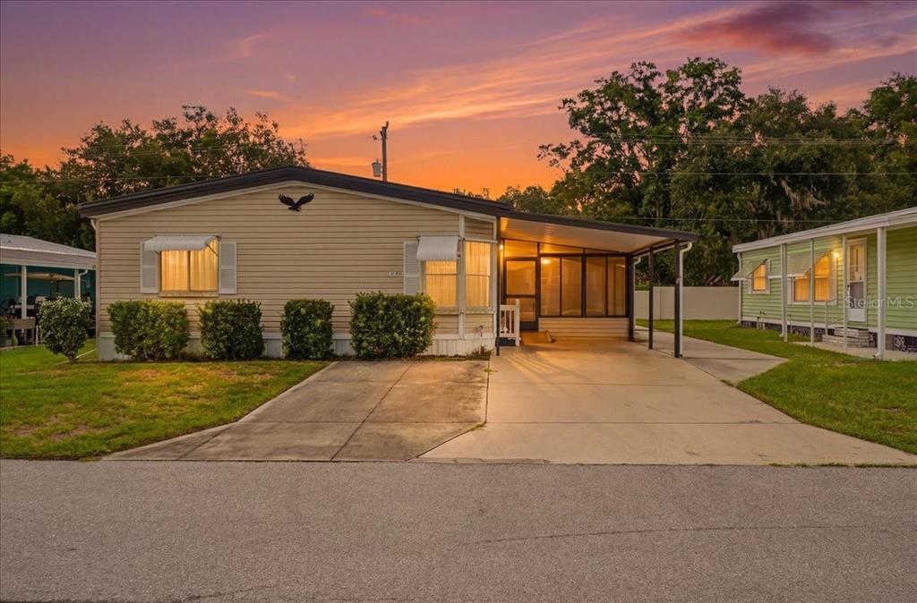 A single-story manufactured home with light siding, a concrete driveway, and an attached screened porch — 1794 FOX HILL DRIVE, LAKELAND, FL