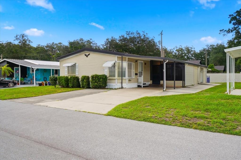 A light yellow mobile home with a carport and a small front lawn — 1794 FOX HILL DRIVE, LAKELAND, FL