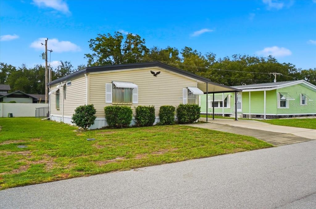A single-story manufactured home with light siding, a concrete driveway, and a covered carport — 1794 FOX HILL DRIVE, LAKELAND, FL