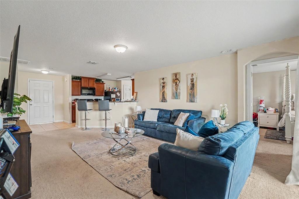 A living room features blue sofas, a glass coffee table, and an open-concept kitchen — 6719 WIREVINE DRIVE, BROOKSVILLE, FL