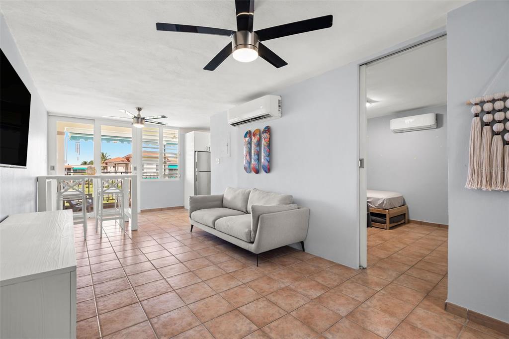 A living room with tile floors, a gray sofa, and an adjacent bedroom — Casa Del Mar II BARRIO MAMEYES UNIT 1806, RIO GRANDE, PR