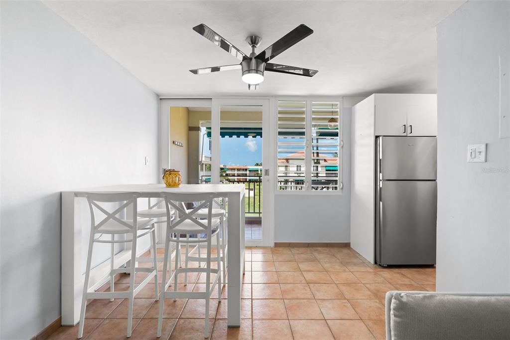 A dining area with white stools and a table sits next to a kitchen refrigerator — Casa Del Mar II BARRIO MAMEYES UNIT 1806, RIO GRANDE, PR