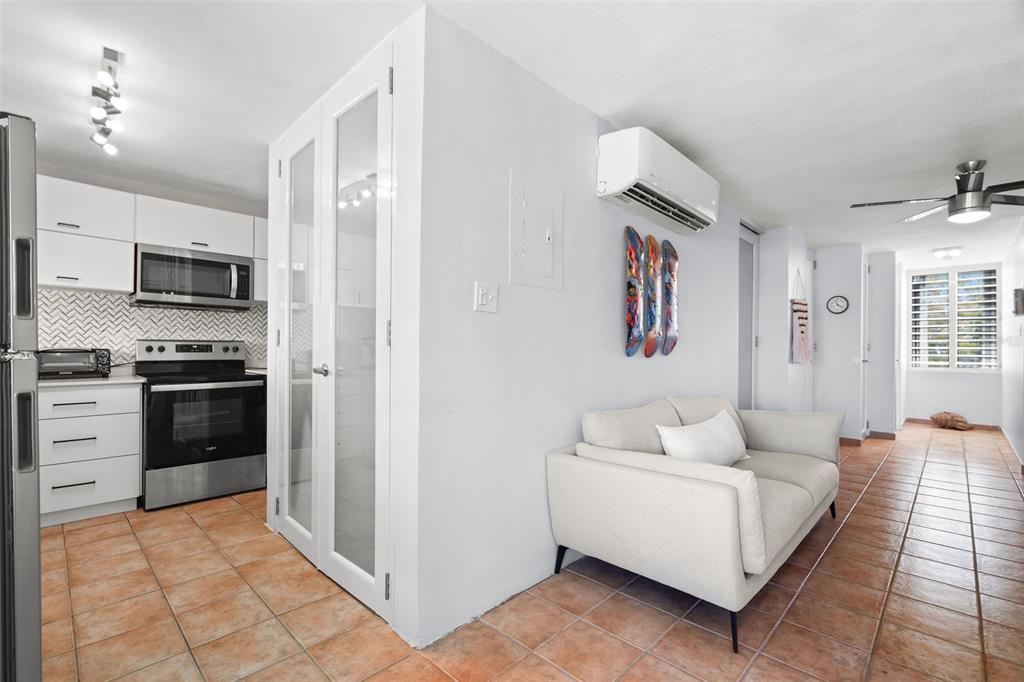 A kitchen with white cabinets and stainless steel appliances sits beside a living area — Casa Del Mar II BARRIO MAMEYES UNIT 1806, RIO GRANDE, PR