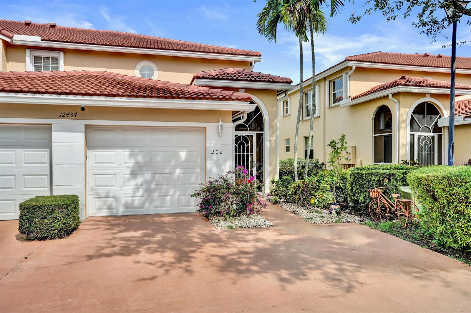 A two-story stucco townhouse with a tile roof, a garage, and a landscaped front yard — 12434 Crystal Pointe Drive # 202, Boynton Beach FL 33437, BOYNTON BEACH, FL
