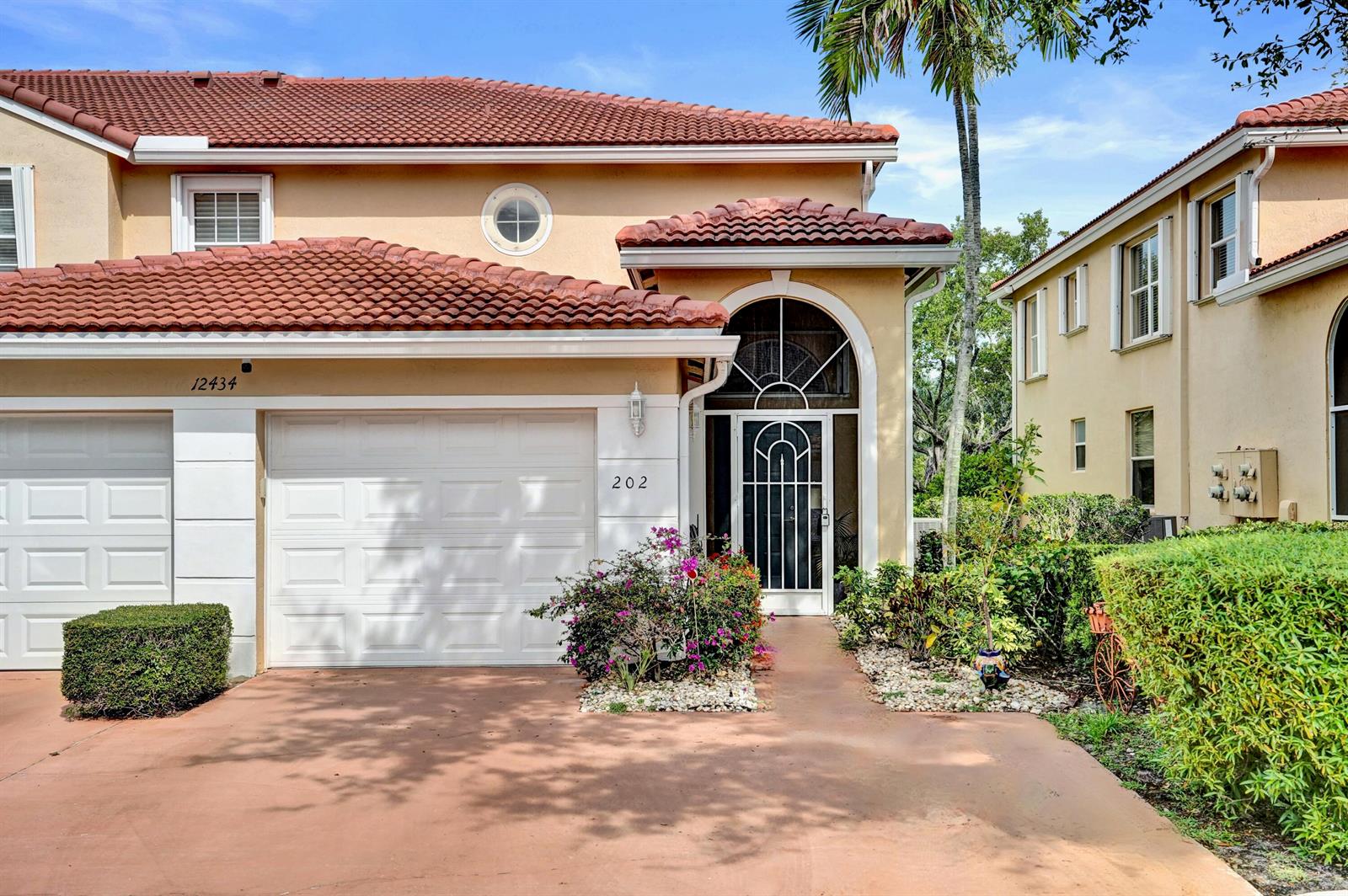 A two-story townhouse with a tan stucco exterior, red tile roof, and a white garage — 12434 Crystal Pointe Drive # 202, Boynton Beach FL 33437, BOYNTON BEACH, FL