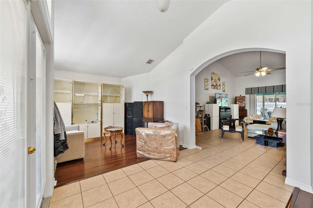 An aerial view shows a suburban neighborhood with houses, green lawns, and a nearby lake — 2651 RAMBLING OAKS WAY, KISSIMMEE, FL