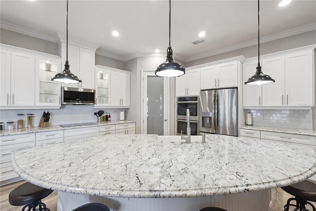 A kitchen features white cabinets, granite countertops, a large island, and stainless steel appliances — 2336 ZALTANA CIRCLE, MINNEOLA, FL