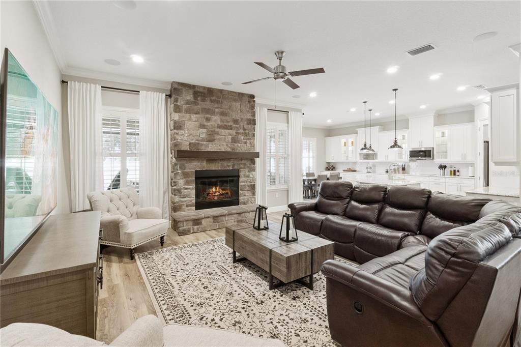 A living room features a stone fireplace, a large sectional sofa, and an open kitchen — 2336 ZALTANA CIRCLE, MINNEOLA, FL