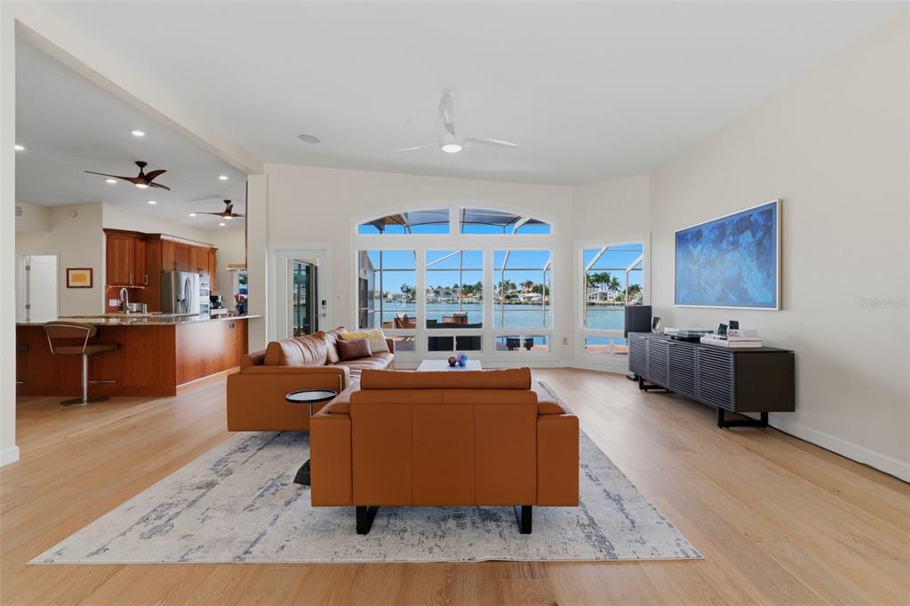 A living room with light wood floors, leather sofas, and a view of the water — 661 79TH CIRCLE S, ST PETERSBURG, FL