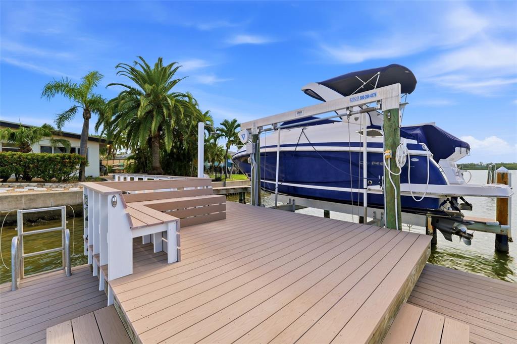 A wooden dock features a built-in bench and a boat lift holding a blue boat — 661 79TH CIRCLE S, ST PETERSBURG, FL