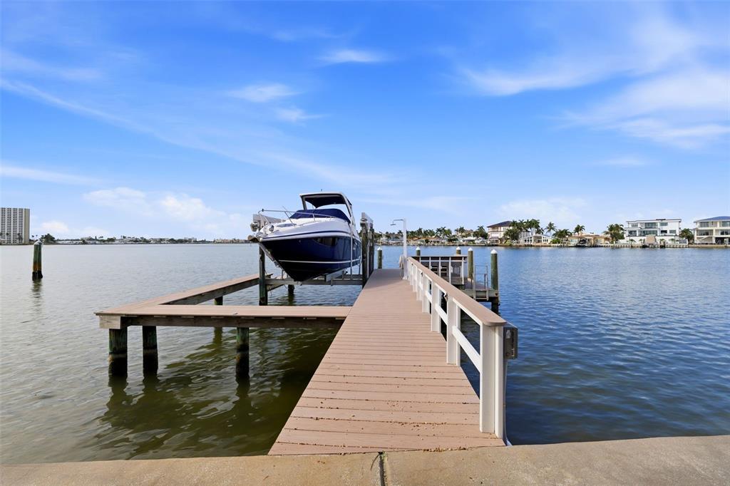 A boat sits on a lift at the end of a wooden dock over water — 661 79TH CIRCLE S, ST PETERSBURG, FL