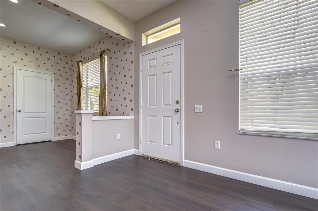 An entryway features dark wood-look flooring, a white front door, and a polka-dot accent wall — 4744 POND RIDGE DRIVE UNIT 1, RIVERVIEW, FL