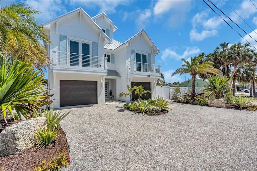 A two-story white house with two garages, balconies, and a gravel driveway with landscaping — 229 WILLOW AVENUE, ANNA MARIA, FL