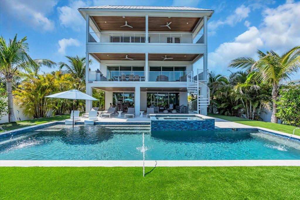 A three-story white house features a swimming pool, hot tub, and balconies with ceiling fans — 229 WILLOW AVENUE, ANNA MARIA, FL