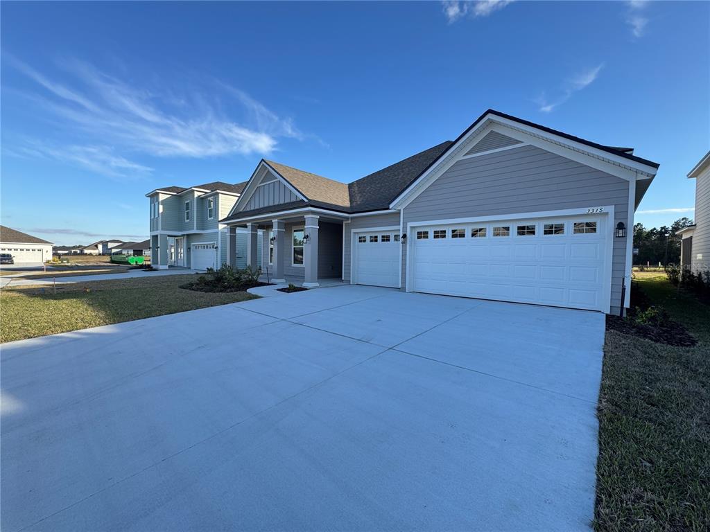 A single-story house with gray siding, a two-car garage, and a covered front porch — 3315 HARVESTERS COURT, GREEN COVE SPRINGS, FL