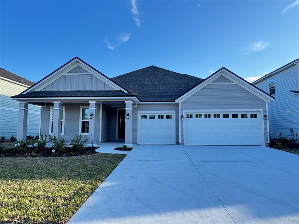 A single-story house exterior features light-colored siding, a covered front porch, and a garage — 3315 HARVESTERS COURT, GREEN COVE SPRINGS, FL