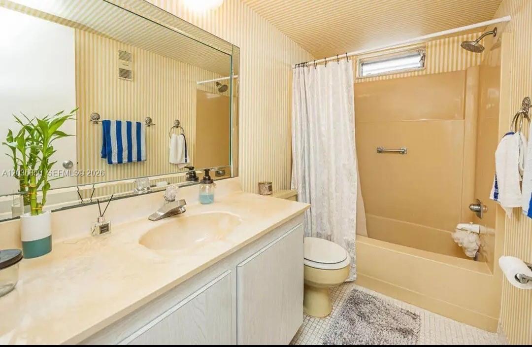 A bathroom features a beige tub-shower combo, a vanity with a mirror, and striped wallpaper — 2615 NE 3rd Ct # 4030, Boynton Beach FL 33435, BOYNTON BEACH, FL