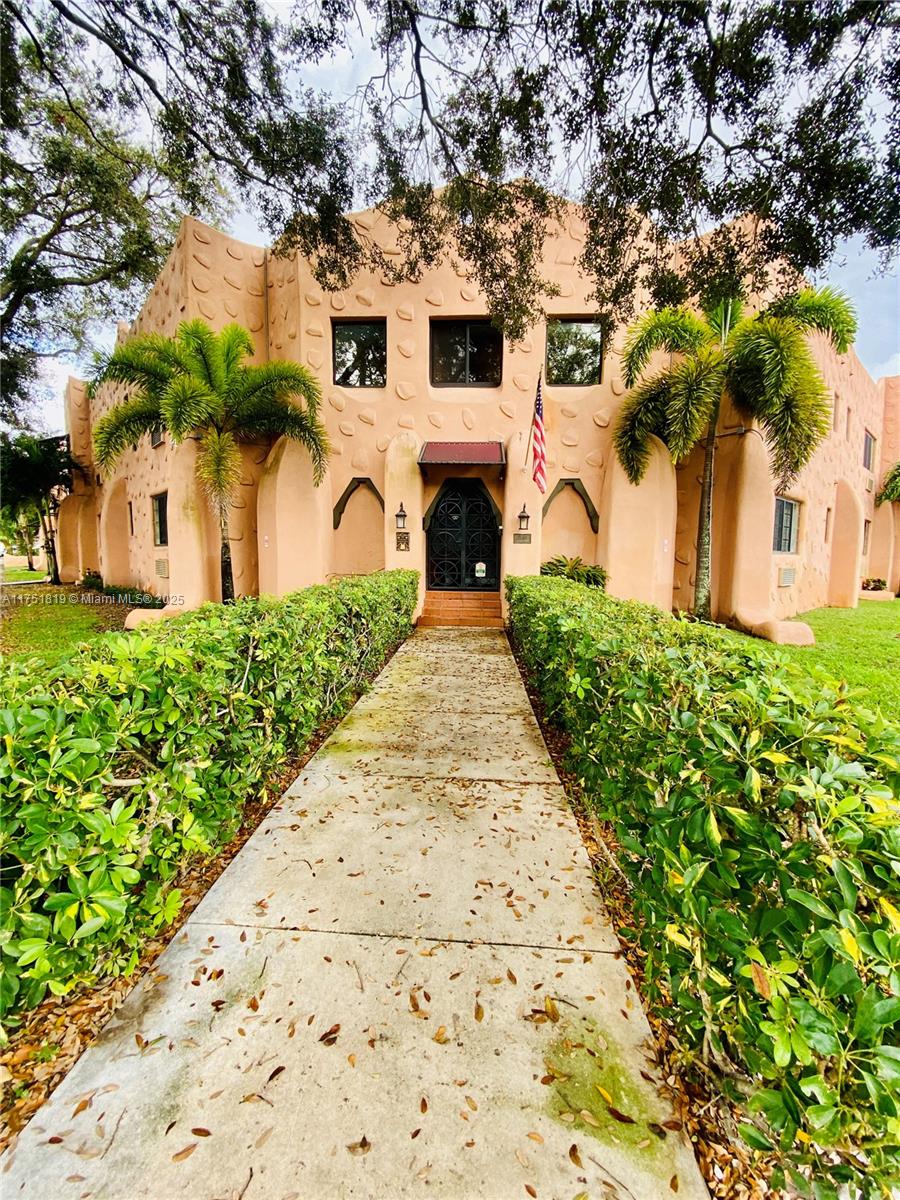 A sidewalk leads to the entrance of a peach-colored building with textured stucco walls — 200 Azure Way, Miami Springs FL 33166, MIAMI SPRINGS, FL