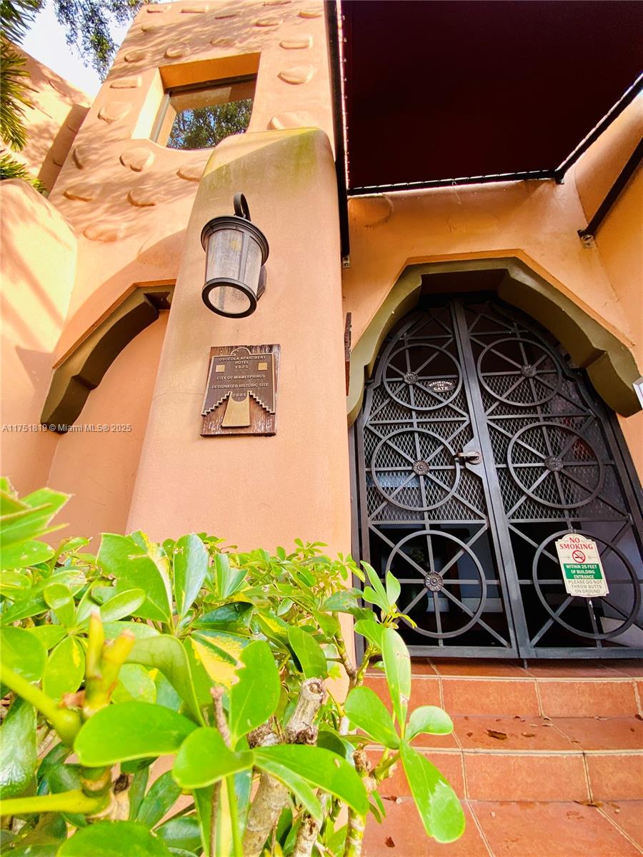 A historic stucco building entrance features a decorative metal gate and a commemorative plaque — 200 Azure Way, Miami Springs FL 33166, MIAMI SPRINGS, FL