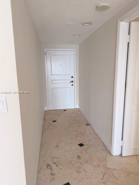 A hallway with light-colored tile flooring leads to a white front door — 2451 Brickell Ave, Miami FL 33129, MIAMI, FL