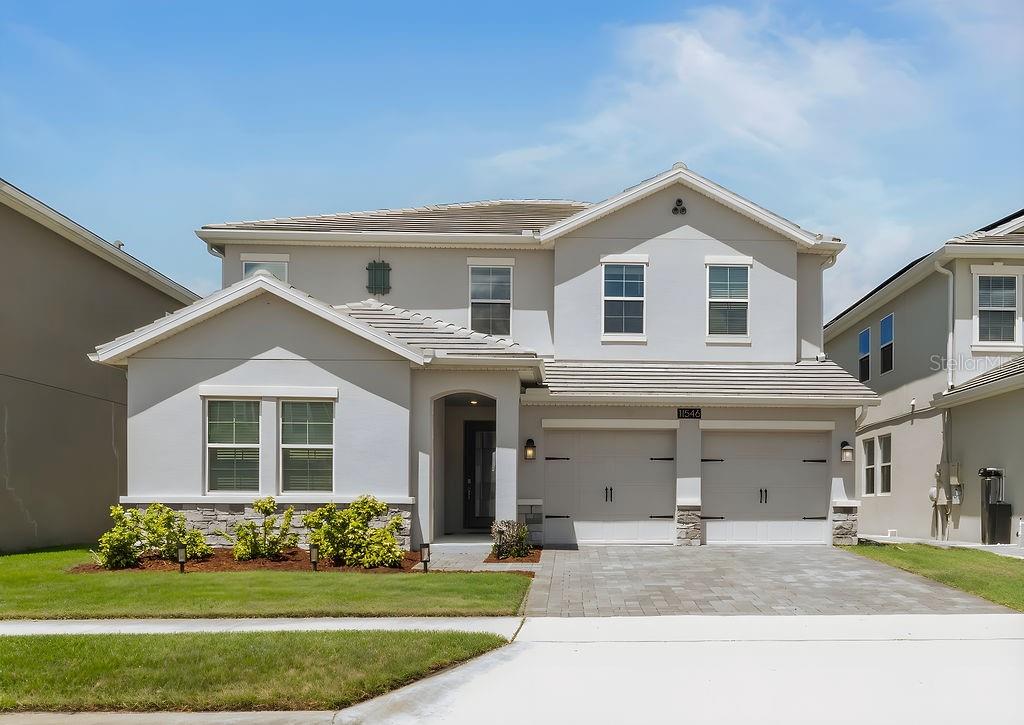 A two-story suburban house with a light gray exterior, stone accents, and a two-car garage — 11546 SATIRE STREET, ORLANDO, FL