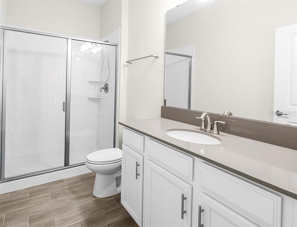 A bathroom features a white vanity with a gray countertop, a toilet, and a glass-enclosed shower — 11546 SATIRE STREET, ORLANDO, FL