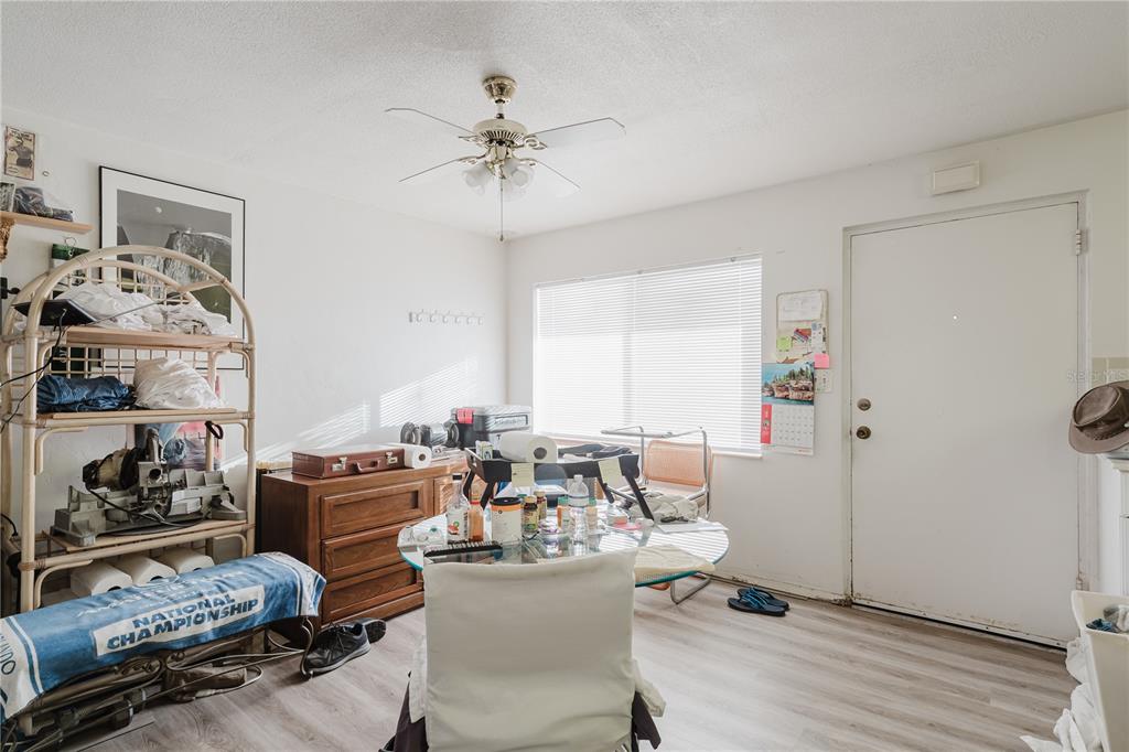 A room with a ceiling fan, a glass table, a wooden dresser, and a white door — 8950 PARK BOULEVARD UNIT 702, SEMINOLE, FL